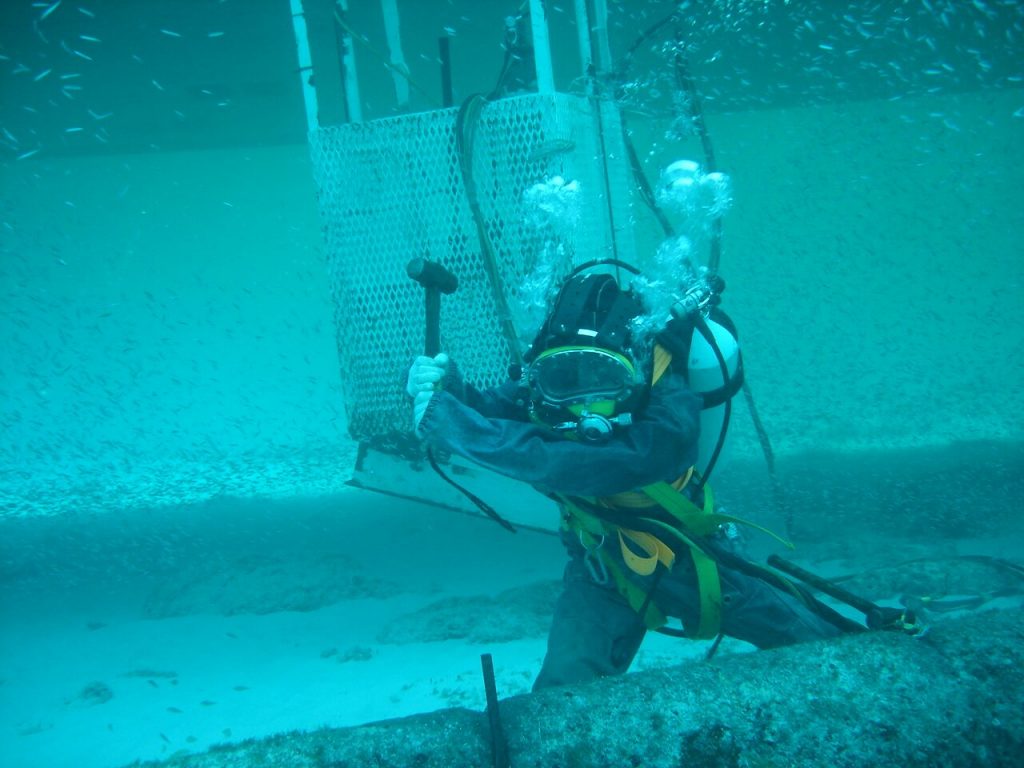 IMCA Commercial Diver using tools and hammer in the water